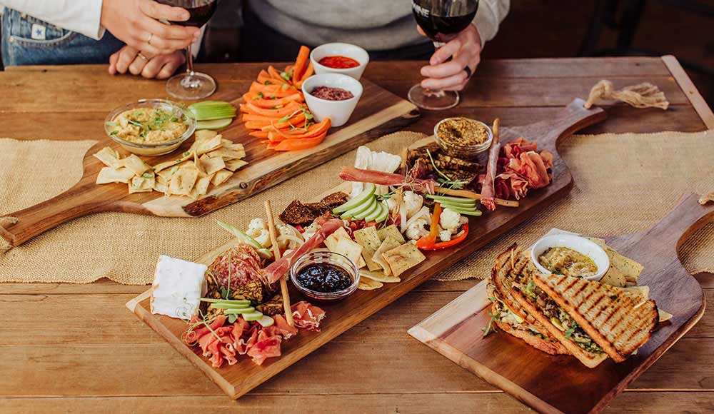 Three Toscana charcuterie boards loaded with delicious snacks